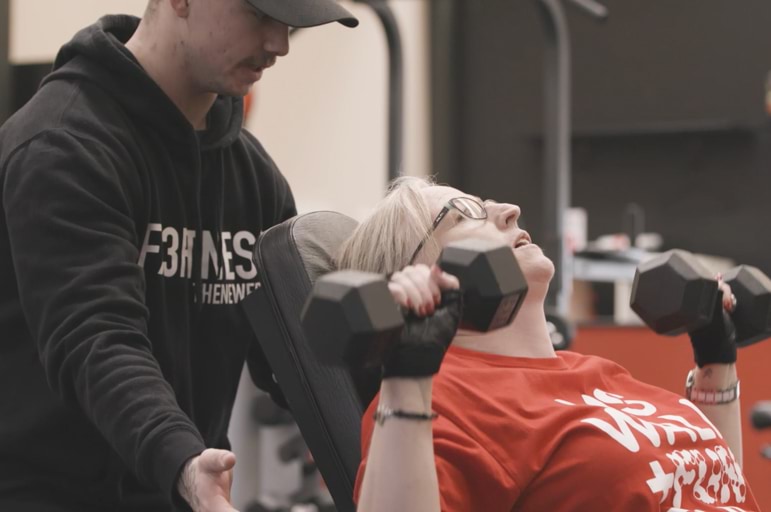 Personal trainer helping a client with weights