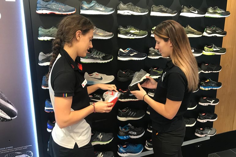 2 TAF team members standing in front of shoe wall in store